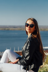 A girl in a leather black jacket and sunglasses