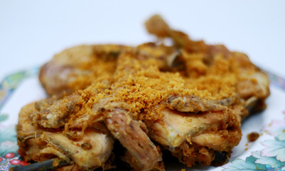 Fried chicken with crispy spiced flakes on white background. Indonesian fried chicken or ayam goreng kremes.