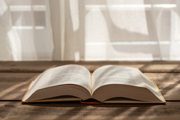 A thick book with open hardcover on a wooden floor