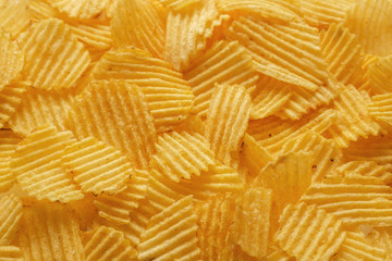Pile of golden potato chips background. Selective focus
