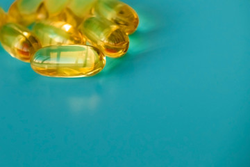 handful of omega 3 capsules on a blue background