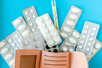 Empty wallet with white tablets of pills on .blue background.