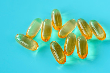 handful of omega 3 capsules on a blue background