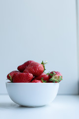 strawberries in a white ceramic glass on white background