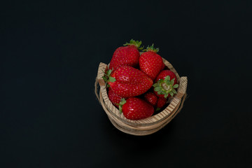 strawberries in a braided basket on a dark background