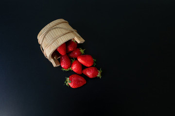 an overturned wooden basket with scattered trawberries