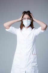 An American doctor in medical clothing and protection grabs his head and hair with his hands and looks in horror at the camera