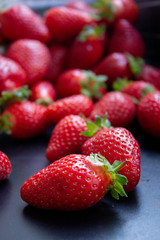a lot of fresh juisy strawberries scatterd on a black table