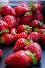 a lot of fresh juisy strawberries scatterd on a black table