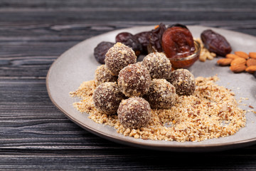 Energy balls in nut crumbs close-up on a plate in the manufacturing process. Made at home from dates, dried fruits and nuts. Sugarless. Useful snack
