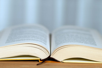 A thick book with open hardcover on a wooden floor