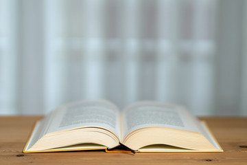 A thick book with open hardcover on a wooden floor