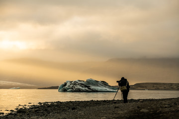 Photographer shooting icebergs in Jokulsarlon glacier lagoon during sunset time - 344720874
