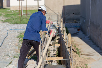A man pours cement mortar from a bucket. Concrete foundation for home