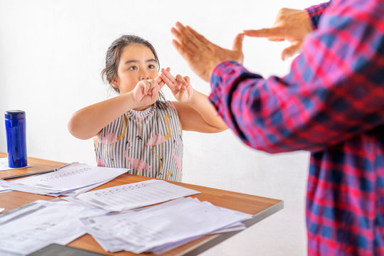 An Asian father is communicating with a deaf daughter