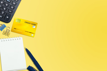 Flat lay or top view of blue pen, Notebook, Credit card with calculator on vivid yellow background