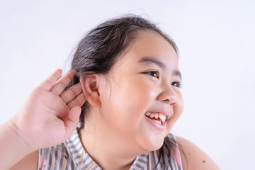 Little asian girl holds her hand near her ear and listening something