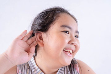 Fototapeta premium Little asian girl holds her hand near her ear and listening something