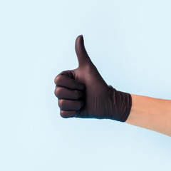 Closeup of female hand in black cosmetic medical hygiene pharmacy gloves showing thumbs up sign...