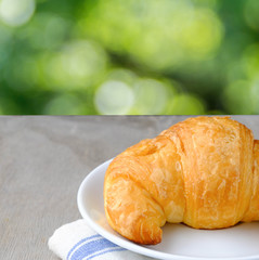 Croissant on white plate on wooden rustic background. the view from the top