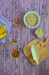Cooking a delicious and healthy breakfast at home. Oatmeal, bananas, almonds. A jug of milk on a wooden chopping board. Ingredients for the preparation of milk porridge