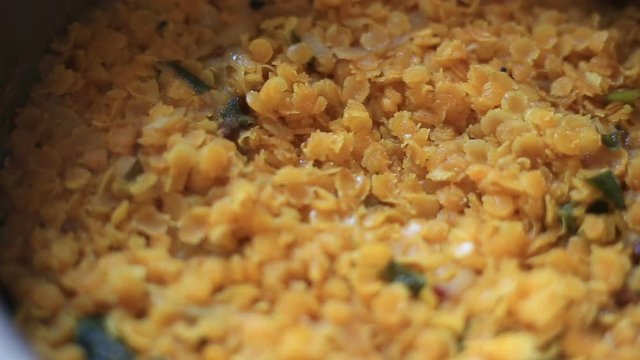 Rotating close up of hot cooked dhal curry with smoke with focus shifting. 