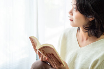 窓際で本を読む女性