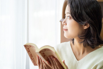 窓際で本を読む女性