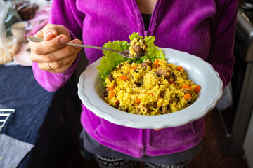Yellow millet grain porridge with vegetables, herbs, spices and mushrooms. Vegan healthy food. Hands