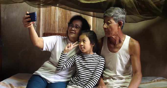 Senior Couple And Granddaughter Taking Photo With Smartphone
