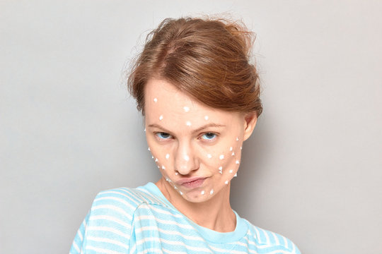 Portrait of funny flirty girl with white drops of face cream on skin