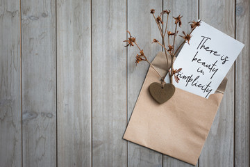 handwritten letter in a brown vintage envelope on wooden background, decoration wooden heart and dried flowers communication,