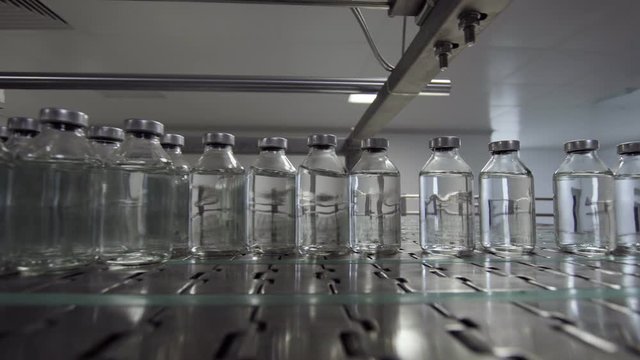 glass bottles filled and sealed with rubber and aluminum caps on medical solution conveyor line medical industry
