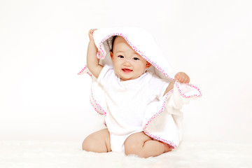白背景の前でタオルを被り一人遊びする女の子の赤ちゃん