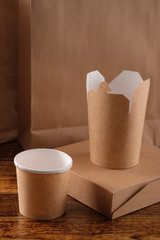 Street fast food paper cups, plates and containers. Eco-friendly food packaging on wooden background. Carering of nature and recycling concept.