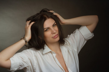 Fototapeta premium brunette in a white blouse on a dark background. Long straight hair