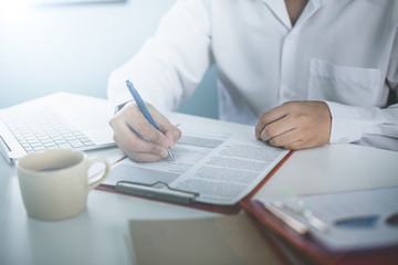 Fototapeta premium Business meeting. A man signs a contract. Male hand with pen makes notes in office.