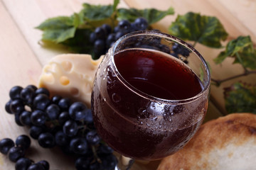 Wine, grape, cheese and bread on table