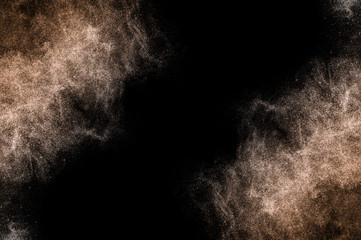 Explosion of brown powder on black background