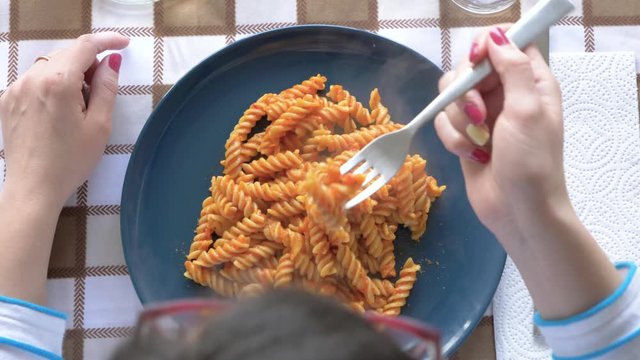 Woman eating fresh pasta with fork, from above