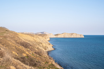 Blue sea water. The steep shore. No people. Daylight.