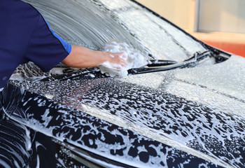 Obraz premium Closeup of black car cleaning, washing and rubbing to remove dust and dirty things by male worker's hand. 