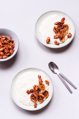Creamy Rice Porridge or Pudding with caramelized bananas and nuts in bowls on grey concrete background. Selective focus