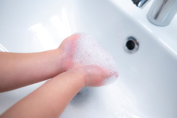 Child washing hands with soap to fight covid-19