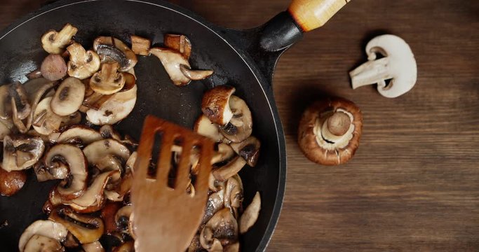 With a spatula stir the mushrooms in a pan with hot steam.