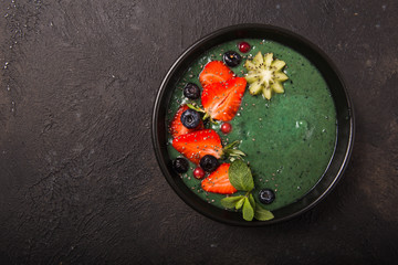 Colorful, healthy food. Acai smoothie bowl. Keto breakfast idea. Fruit curd smoothie, acai. Breakfast with green spirulina, strawberry, chia, kiwi in black plate