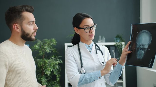 Patient and doctor are looking at x-ray images in clinic office talking discussing disease. People, healthcare and contemporary hospitals concept.