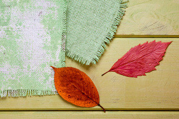 .A canvas napkin and tree leaves lying on a wooden surface. Background for fall and natural objects.