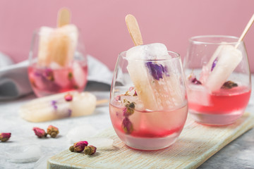 Color food. Cocktail glasses of pink rose champagne, or lemonade with dry rose buds, ice-cream