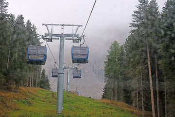 Cabin of Cable car lift arrive to top of the mountain with place of rest, restaurant and hotel in foggy day. Dolomites, Italy. Selective focus.